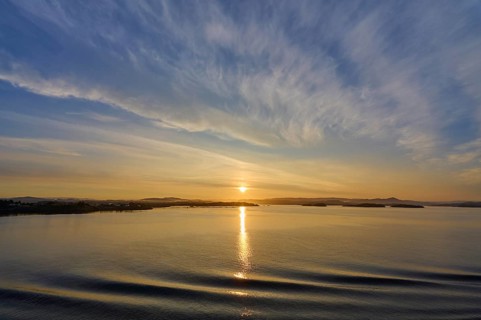 Calm seascape at sunrise with soft clouds and island in the background, Bergen, Vestland, Norway