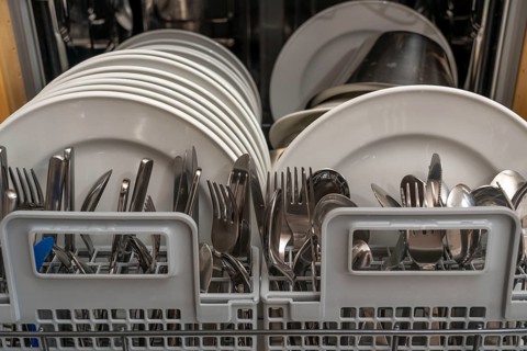 Dishwasher, full, with cleaned crockery, cutlery, cooking utensils
