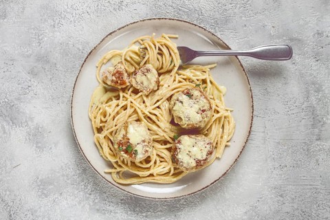 Spaghetti with chicken meatballs, with cream sauce, and parmesan cheese, and decorated with
