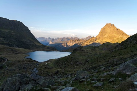 Stunning view of the Midi d'Ossau peak and a serene lake in the French Pyrenees during sunset The