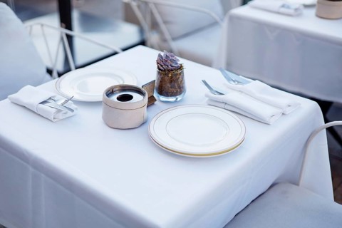 A beautifully arranged dining table features a crisp white tablecloth with elegant tableware,