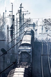 Deutsche Bahn AG tracks backlit with goods train. Overhead line, signals and infrastructure.