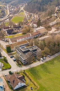 Village with houses and roads in a hilly landscape surrounded by trees from an aerial perspective,