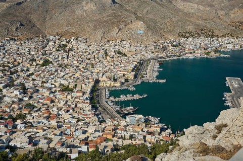 Aerial view of a densely built city on the seashore with mountains, Pothia, main town, port,