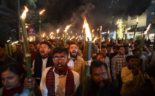 Members of the All Assam Students' Union (AASU) take part in a flaming torch rally and shout