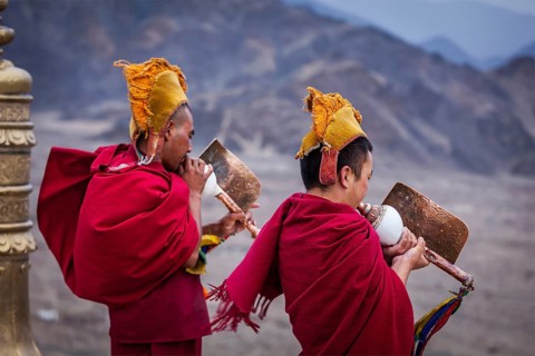 THIKSEY, INDIA, SEPTEMBER 4, 2011: Two Tibetan Buddhist monks blowing conches during morning pooja,