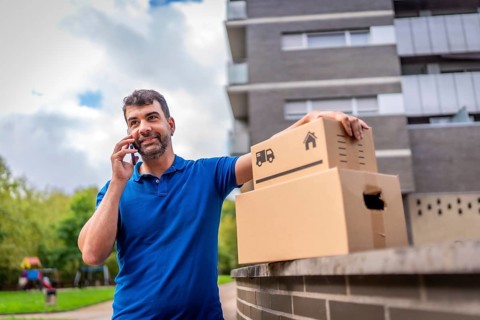 Delivery man talking to the mobile standing next to boxes outdoors in the city