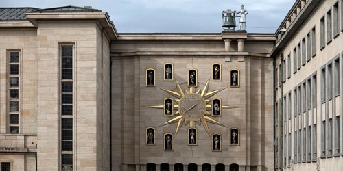 Large golden wall clock with twelve figures at the back of the Dynasty Palace, Brussels, Belgium