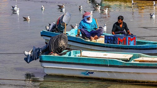 Fishermen working on their boats in the harbour of Mirbat, Dhofar Province, Arabian Peninsula,