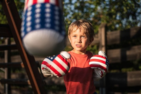 Cute boy boxing bag in the garden during sunny afternoon