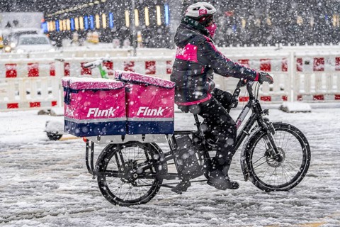 Winter weather, heavy snowfall, city centre traffic, courier of the delivery service Flink on