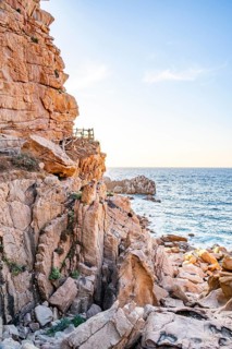 A little trail passing the rocks at the coastline with blue water at Costa Paradiso on a sunny day