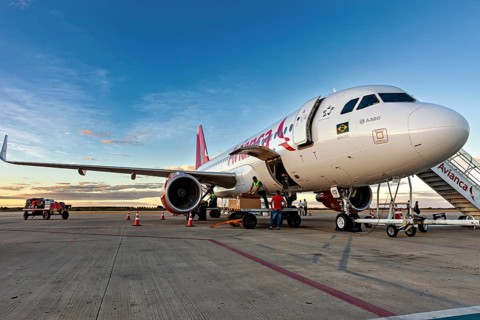 Passenger plane on tarmac, people preparing it for flight as the sun sets, airplanes on the runway