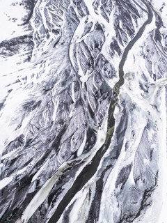 Aerial view of a snow-covered Icelandic winter landscape showcasing a winding river cutting through