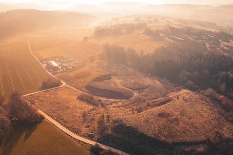 Aerial view of a vast landscape with hills and fields in warm sunset light, landfill, Gechingen,