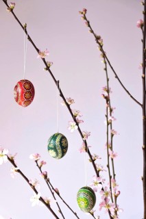 Blooming branches of a peach tree in a vase decorated with Easter eggs, spring, Germany
