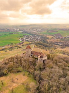 Historic castle on a wooded hill overlooking extensive fields and a town, Lichtenberg Castle,