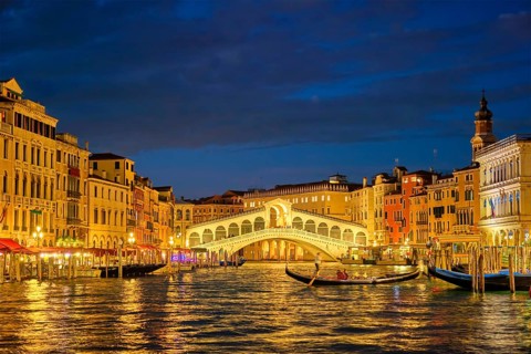 Famous Venetian tourist landmark Rialto bridge (Ponte di Rialto) over Grand Canal illuminated at