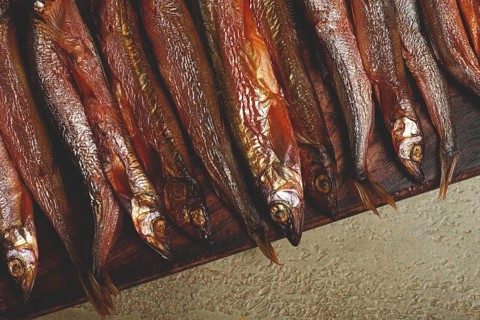 Cold smoked capelin, on a wooden chopping board, no people