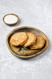 Golden potato cakes on a rustic wooden plate, garnished with fresh rosemary. A small bowl of sour