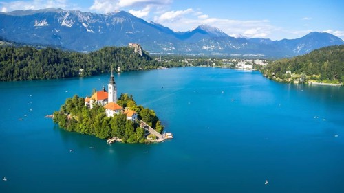 Aerial view of lake bled featuring the assumption of mary church on a small island, with kayakers