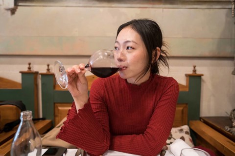An asian female tourist savors a glass of red wine in Segovia, Spain. Her relaxed demeanor and