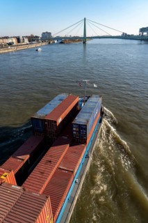 Container cargo ship on the Rhine, heading south, the crane houses in Cologne at the