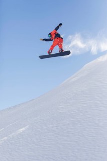 A snowboarder performs an impressive aerial trick, captured mid flight against a crisp blue sky.