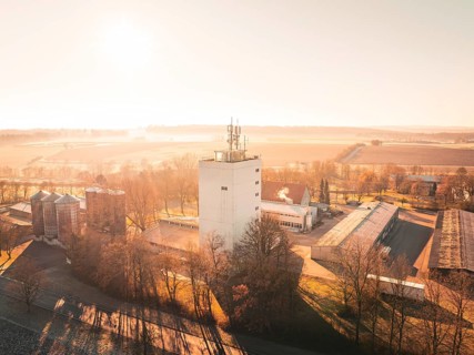 Industrial hall in a rural setting at sunset, surrounded by fields, Agricultural Experiment