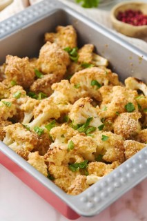 Oven baked cauliflower pieces coated in breadcrumbs and sprinkled with melted cheese and parsley,