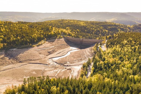 Landscape with dry riverbed and surrounding autumnal forests, emptied Schwarzenbach dam, Forbach,