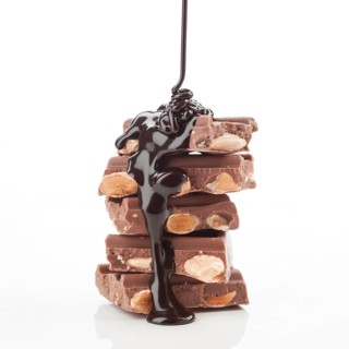 A mouthwatering stack of almond filled chocolate bars is being covered with rich, melted chocolate.