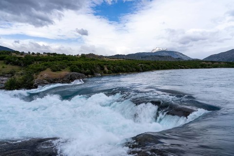 Confluence of Río Baker and Río Neff, turquoise rapids with spray, wooded banks and snow-capped