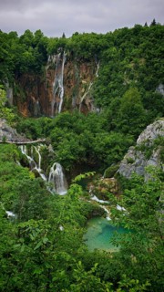 Waterfall in the middle of a wooded gorge with clear lakes, Plitvice Lakes National Park, Croatia