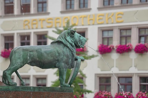 Market fountain with lion figure and water jet, blurred inscription Ratsapotheke, blur, pharmacy,