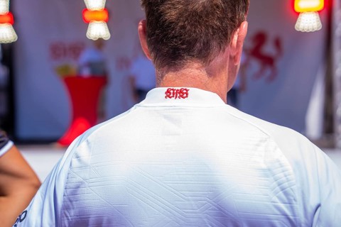 Back view of a man wearing a white shirt with a sporty and elegant touch, red lettering in the