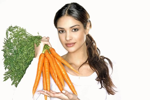 Beautiful young woman holding carrots, 35 years old, brunette woman, bunch of roots, vegetables,