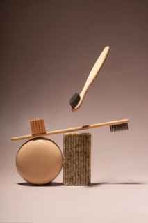 Aesthetic arrangement of bamboo toothbrushes balanced on natural soap and a round beige object, set