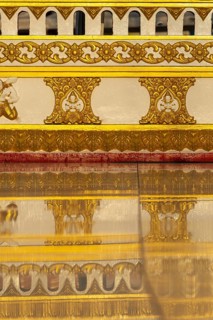 Wall decorated with golden ornaments around the chedi in Wat Phra That Phanom at sunrise, temple