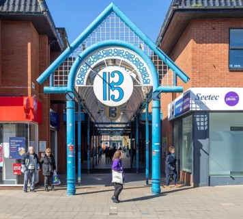 Shoppers on street with shops and entrance to The Britten Shopping centre, Lowestoft, Suffolk,