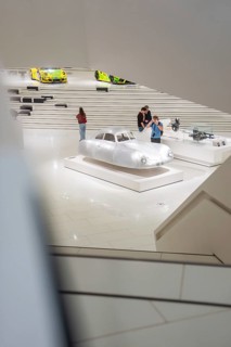 Exhibition of a silver vehicle in a modern museum room with visitors, Porsche Museum, Stuttgart,