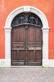Classic wooden door with decorative metal ornaments in the skylight and historical inscription in