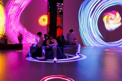 Visitors, immersive art exhibition, colorful projections on walls and floors, dynamic light trails,
