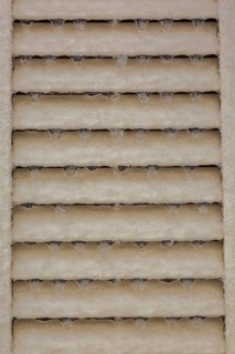 Close-up of icicles hanging from tan coloured angled slats on decorative tan colored louver panel