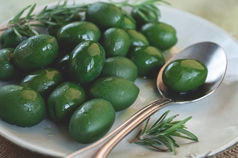 Chalkidiki olives, classic Greek green olive, on a plate, with a spoon, top view, no people