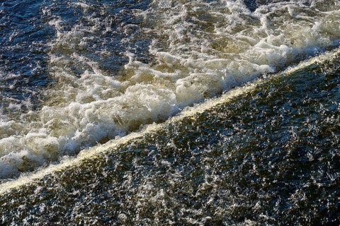 The picture shows the powerful movement of water flowing and splashing over an edge,