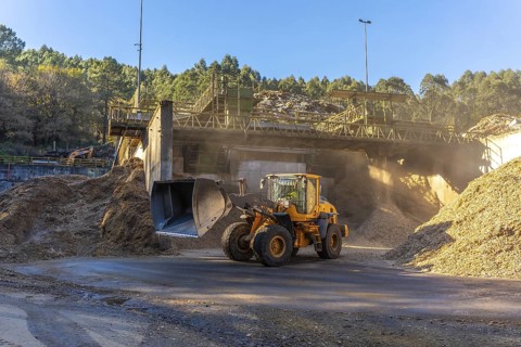 Full length wide view photo of an excavator working in the wood section of a recycling plant