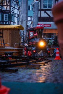 Illuminated miniature train on wet cobblestones at a Christmas market, Christmas market Calw, Black