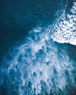 Aerial photograph capturing a surfer in action amidst Portugal's vibrant waves. The image showcases