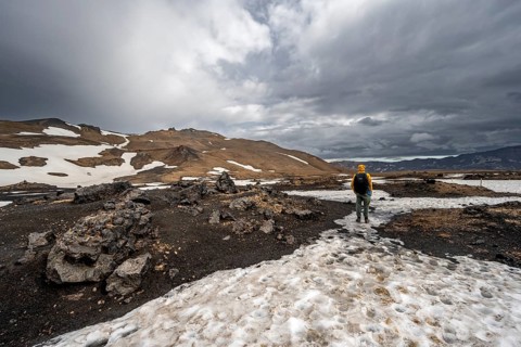 Hikers in snow-covered volcanic landscape with volcanic sand and petrified lava, crater of Askja